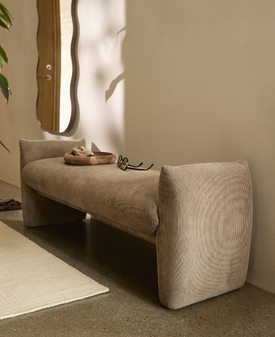 Bänk i grå textil placerad på betongolv.