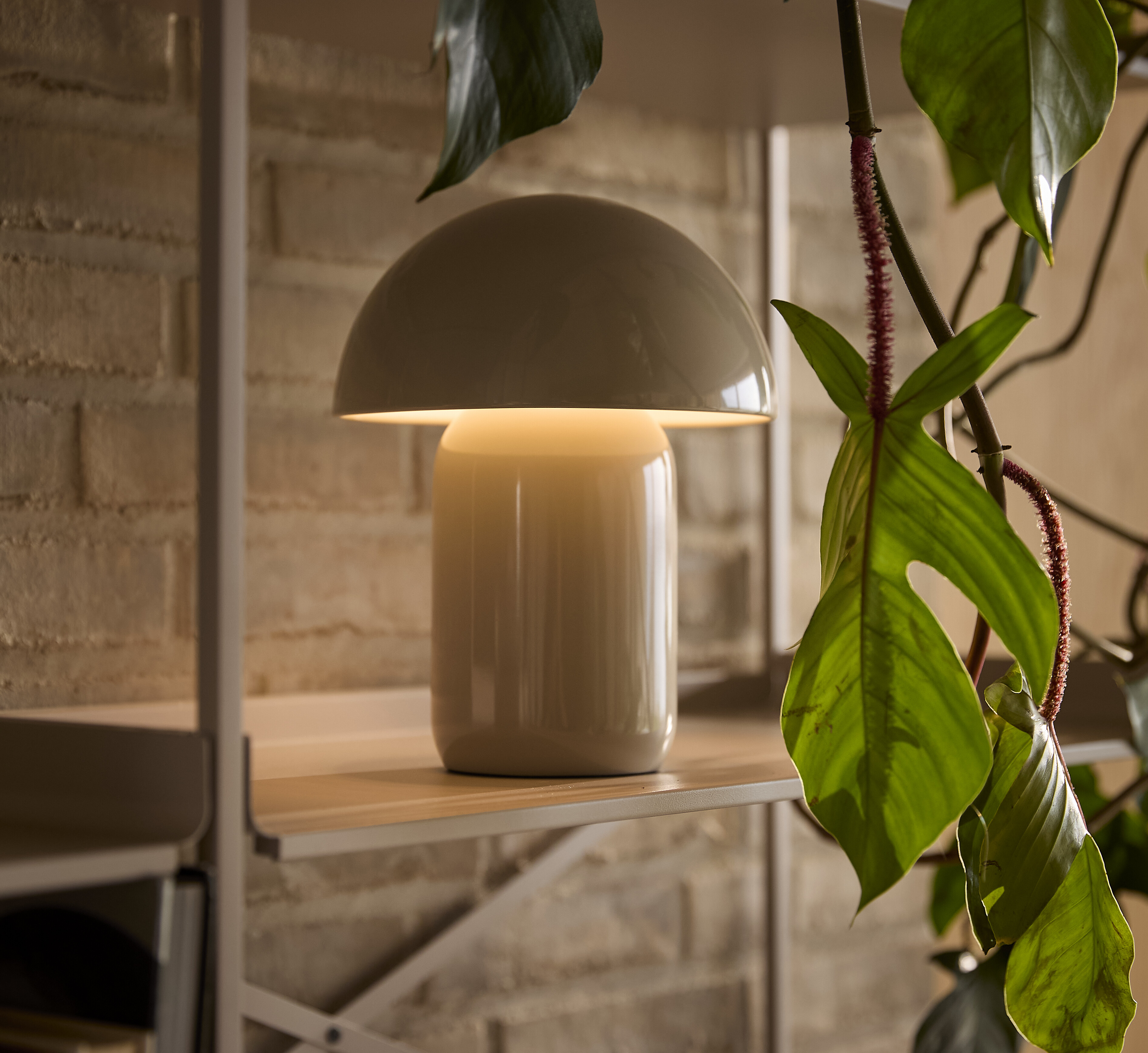 Bordslampa med rund kupa placerad på hylla.