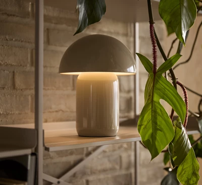 Bordslampa med rund kupa placerad på hylla.