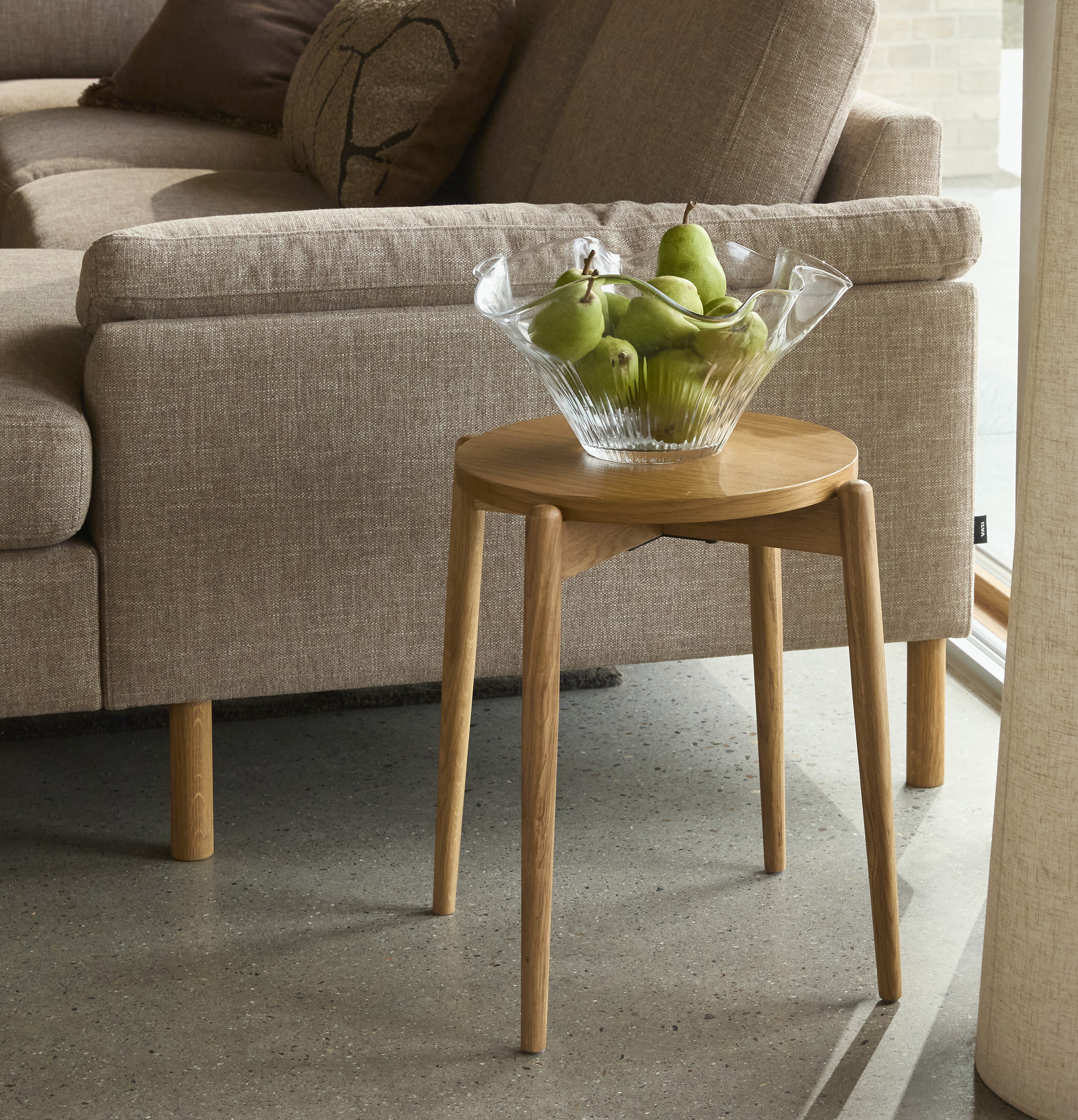 Enkel träpall placerad vid soffan.