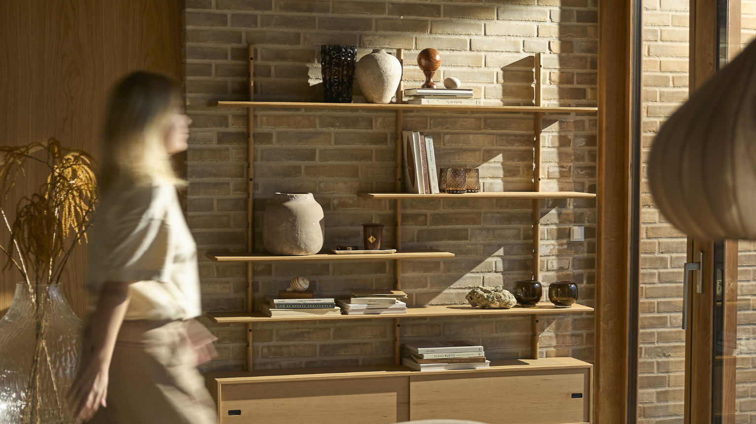 Kvinna som går framför hylla på väggen