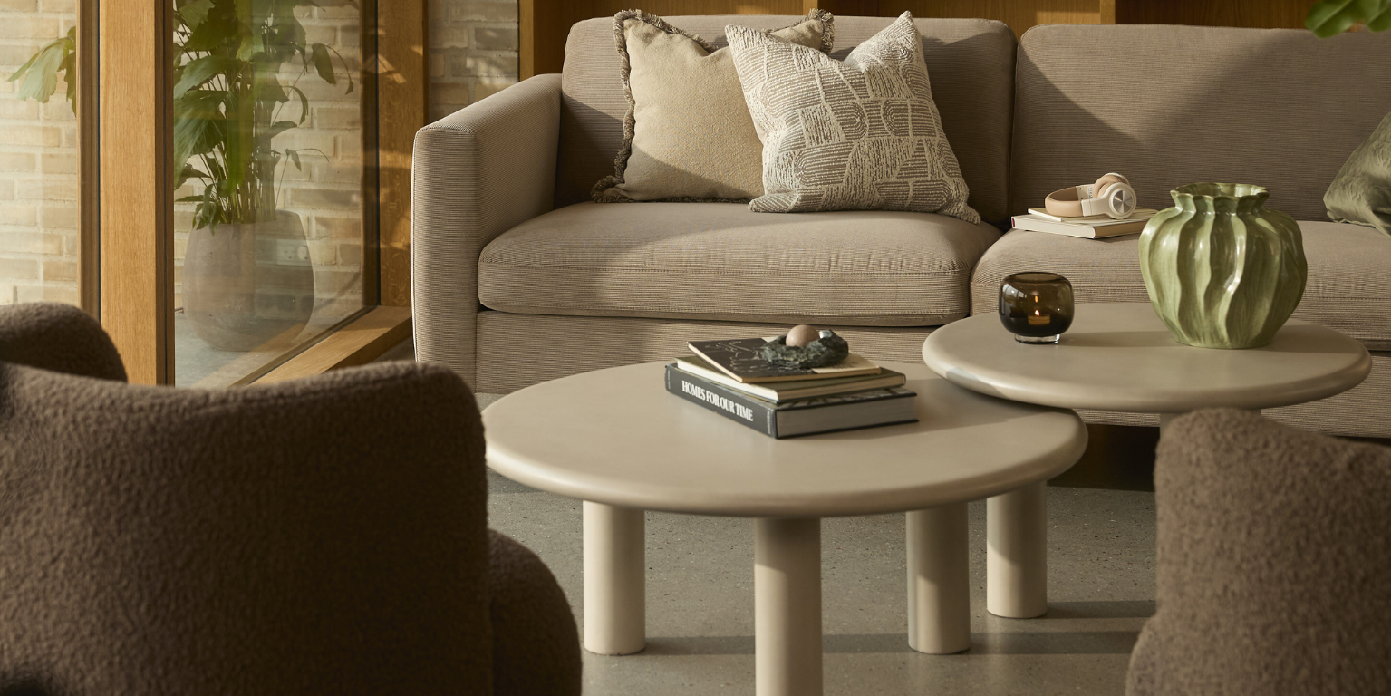 Två lounge­bord i beige placerade i ett ombonat vardagsrum framför soffan.