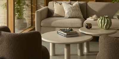 Mesa Två loungebord i beige placerade i ett ombonat vardagsrum framför soffan.