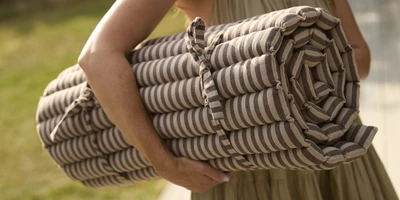 Design Uden Navn 2026 01 15T111834.941 Kvinna som bär en hoprullad trädgårdsdyna.