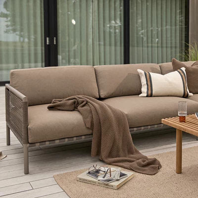 Loungesoffa i mörkbruna nyanser placerad på terrassen.