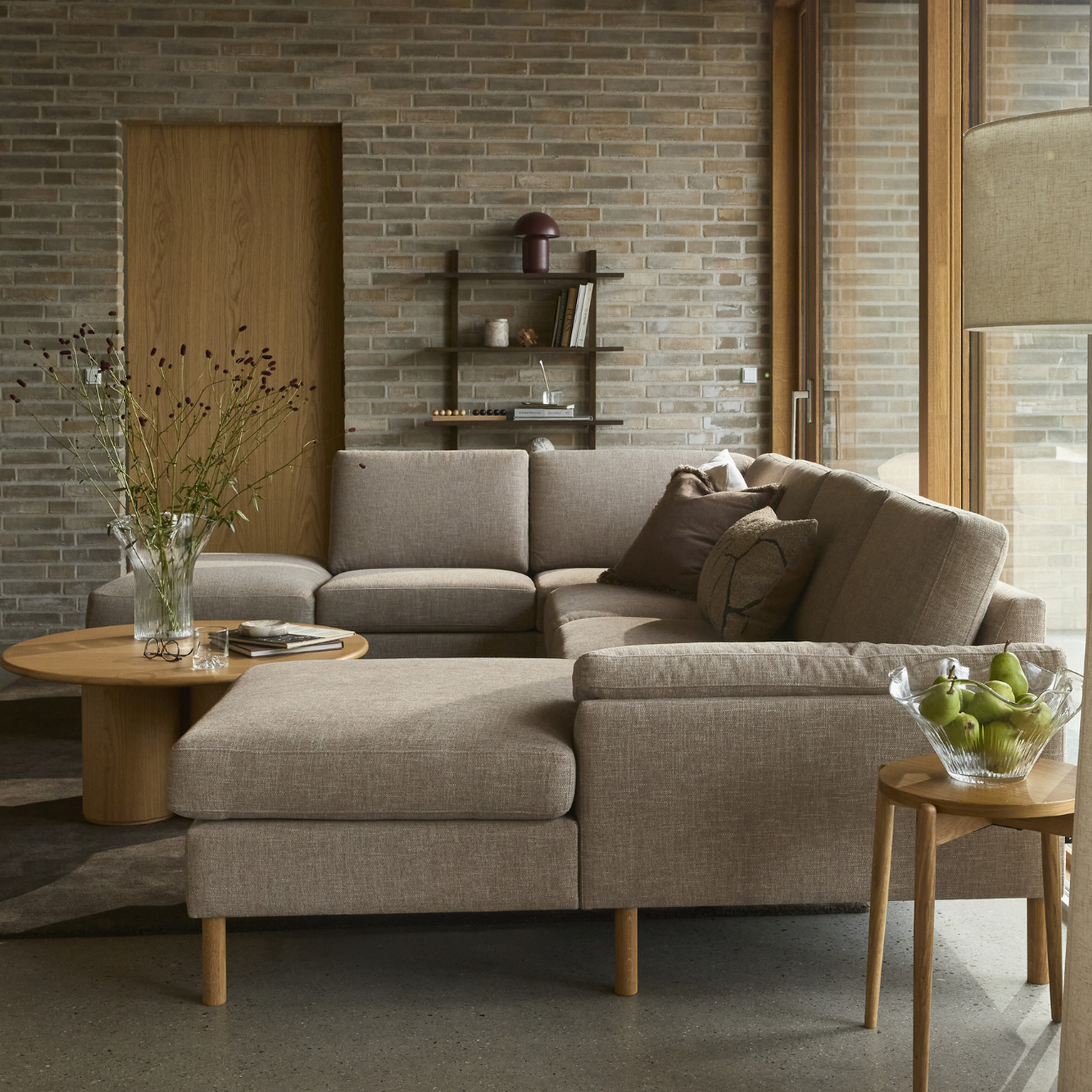 Ombonat vardagsrum med stor U-soffa i mörkgrå textil.