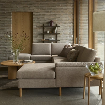 Ombonat vardagsrum med stor U-soffa i mörkgrå textil.