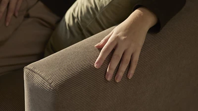 Signatur (2) Hand som rör vid soffan.