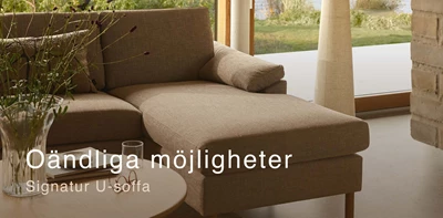 Närbild av schäslong på gråaktig soffa i vardagsrummet.