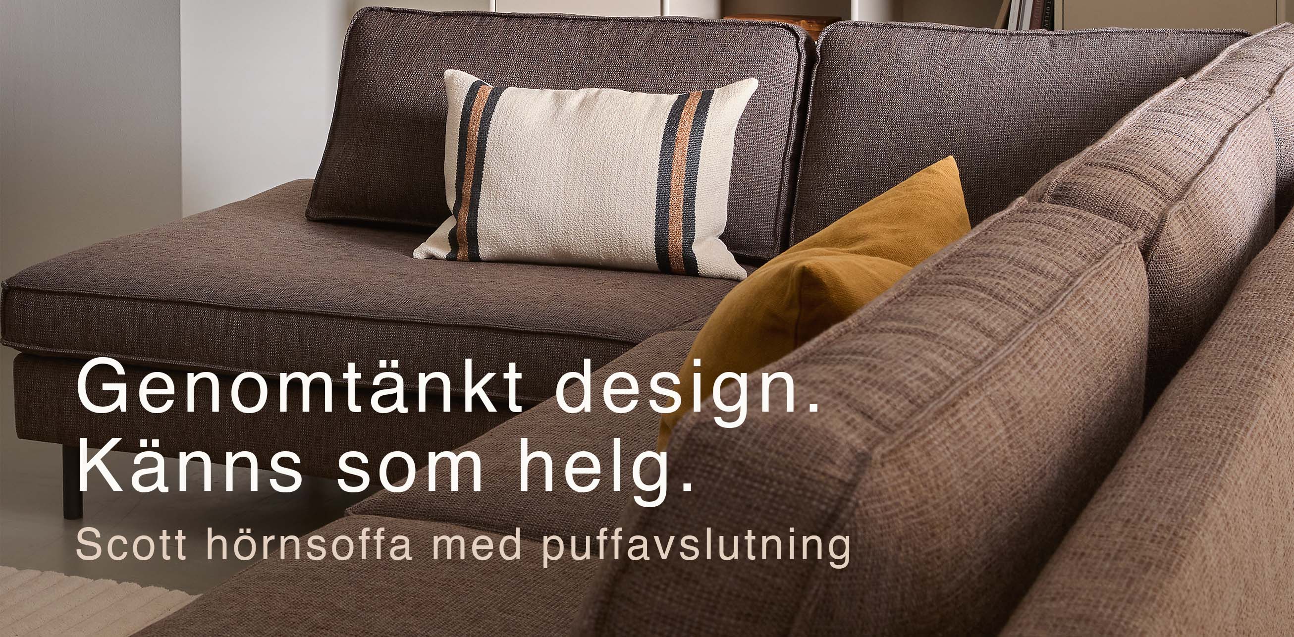 Grå soffa med två kuddar i orange nyanser.