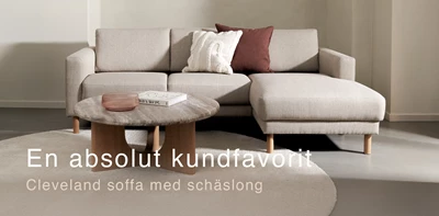 Gråaktig soffa med schäslong tillsammans med runt soffbord och rund matta.