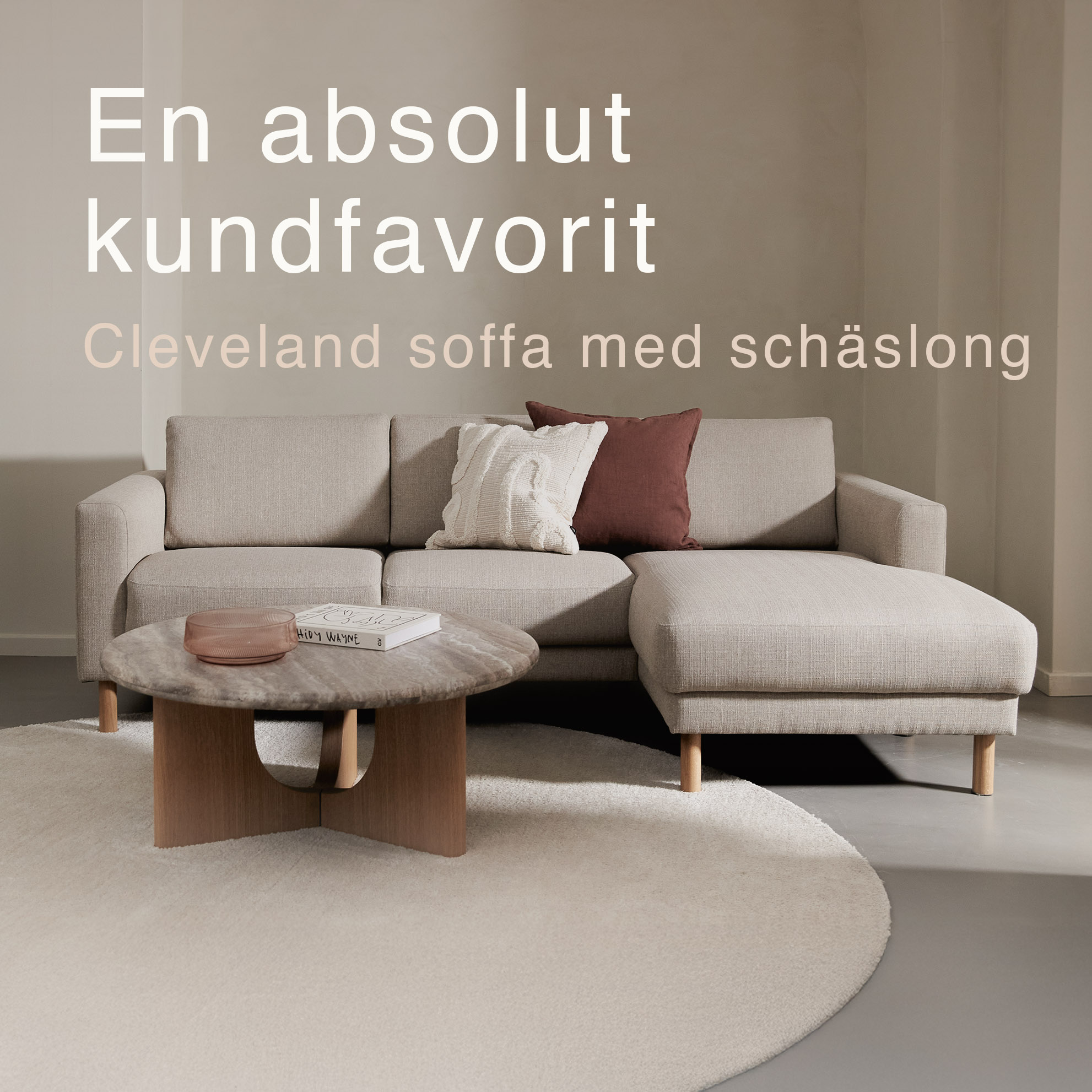 Gråaktig soffa med schäslong tillsammans med runt soffbord och rund matta.