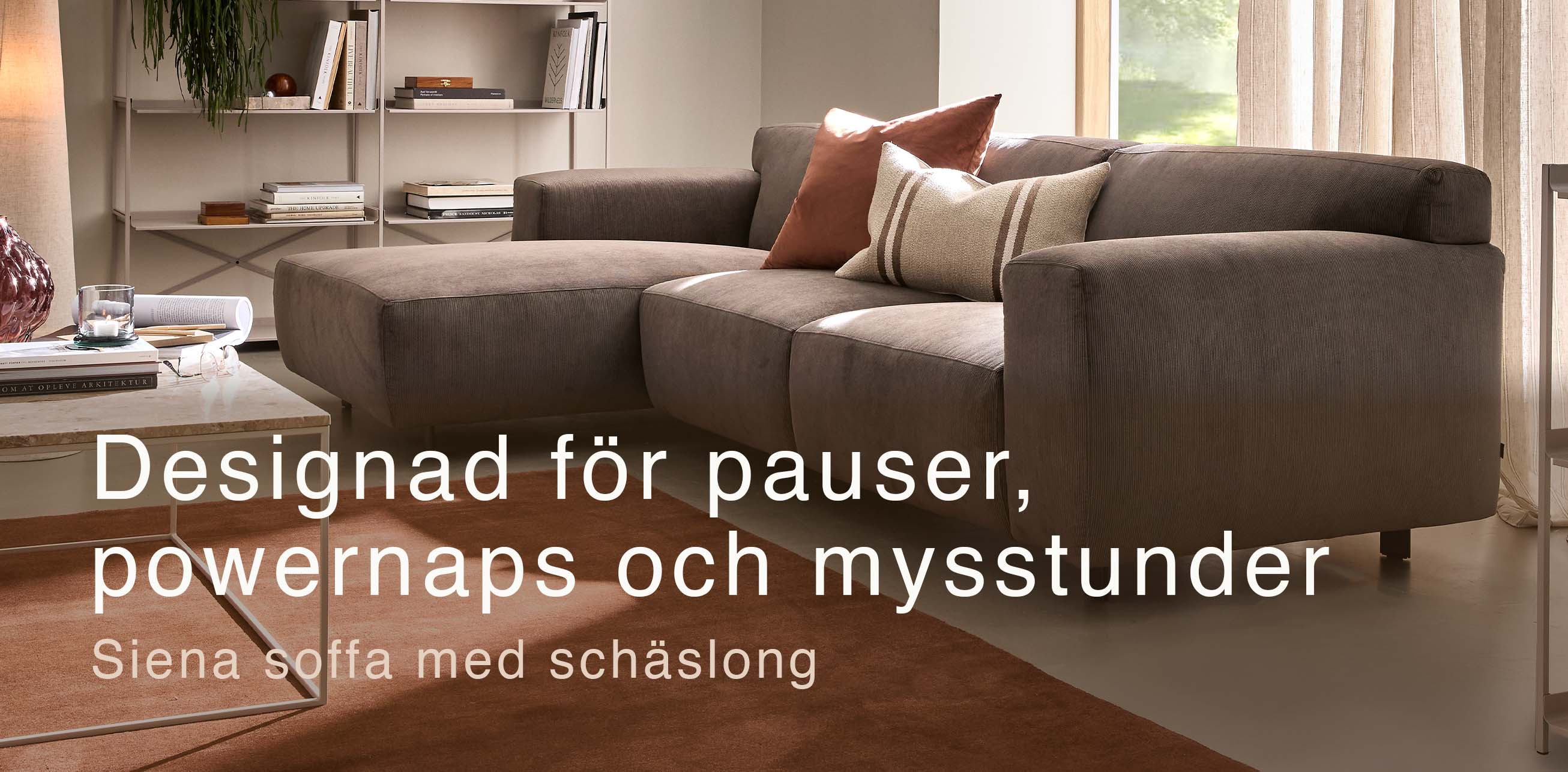 Gråaktig soffa med schäslong och röd matta.