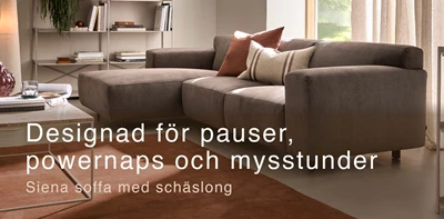 Gråaktig soffa med schäslong och röd matta.