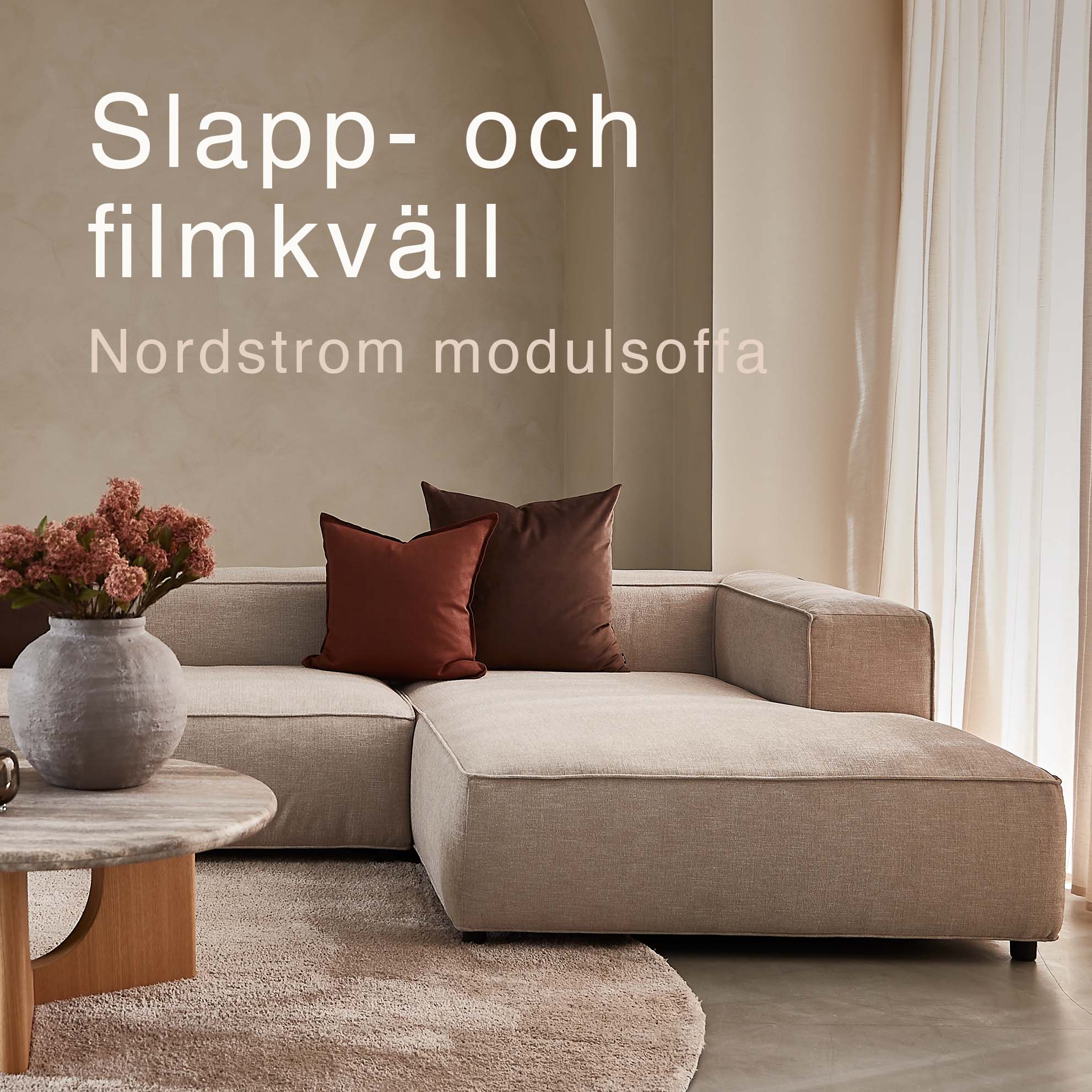 Djup soffa i vardagsrummet med röda kuddar.