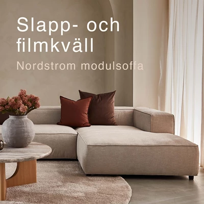 Djup soffa i vardagsrummet med röda kuddar.