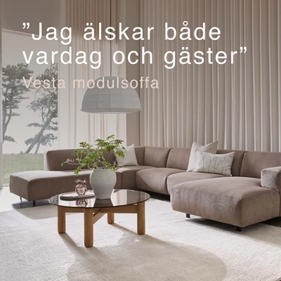 Beigefärgad U-soffa i vardagsrum med stort fönster.