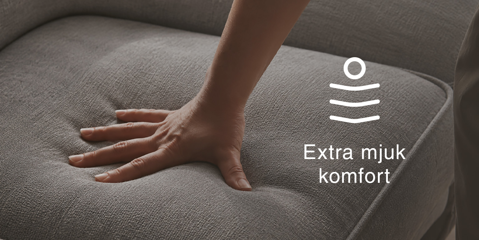 Närbild av en hand som trycker djupt ner i en stoppad sittyta med text och ikon för extra mjuk komfort.