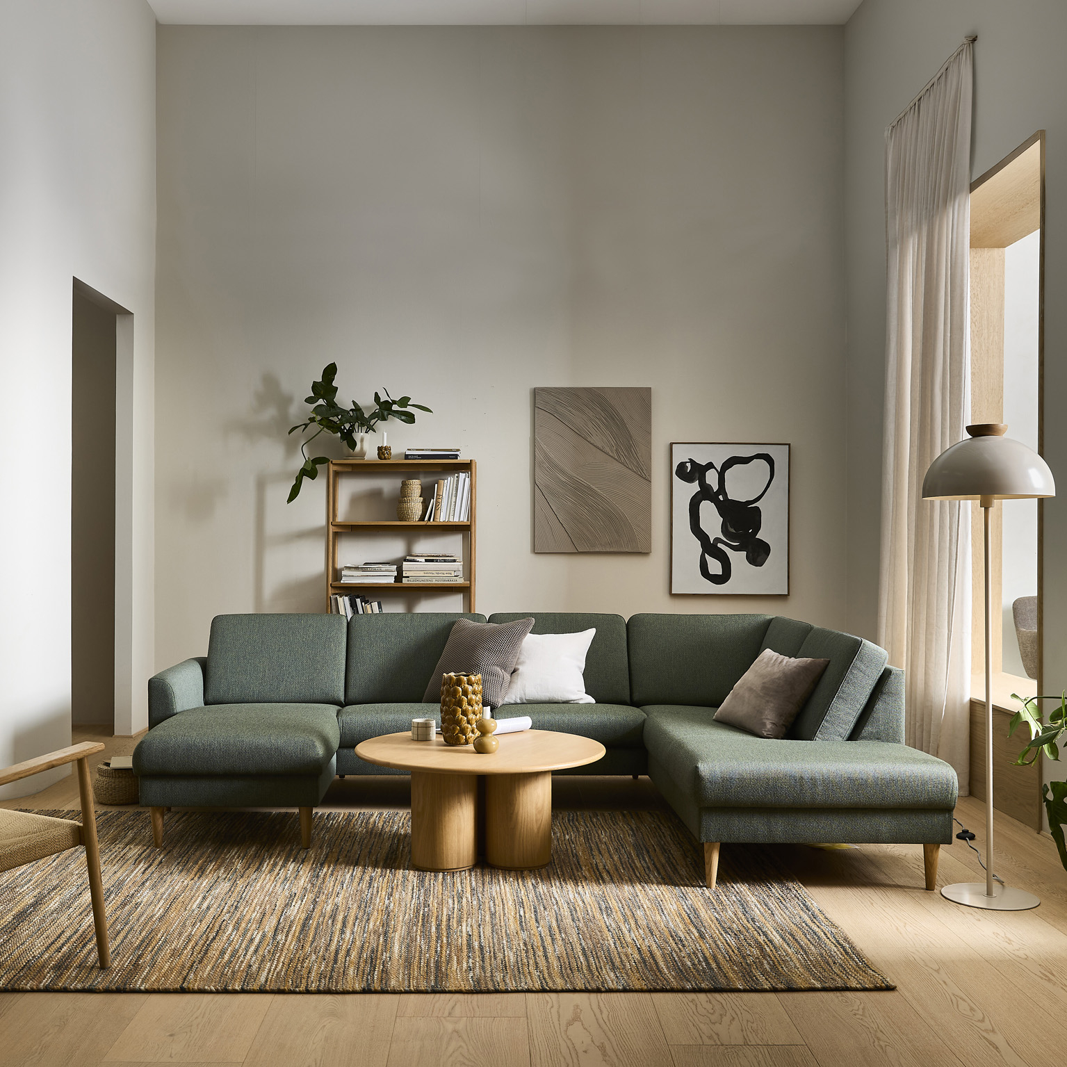 Grön Linea-soffa med schäslong och kuddar i ett ljust vardagsrum