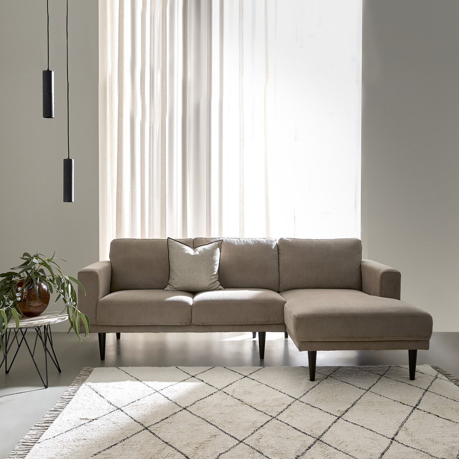 Beige Mexico-soffa med schäslong och mörka ben i ett ljust vardagsrum